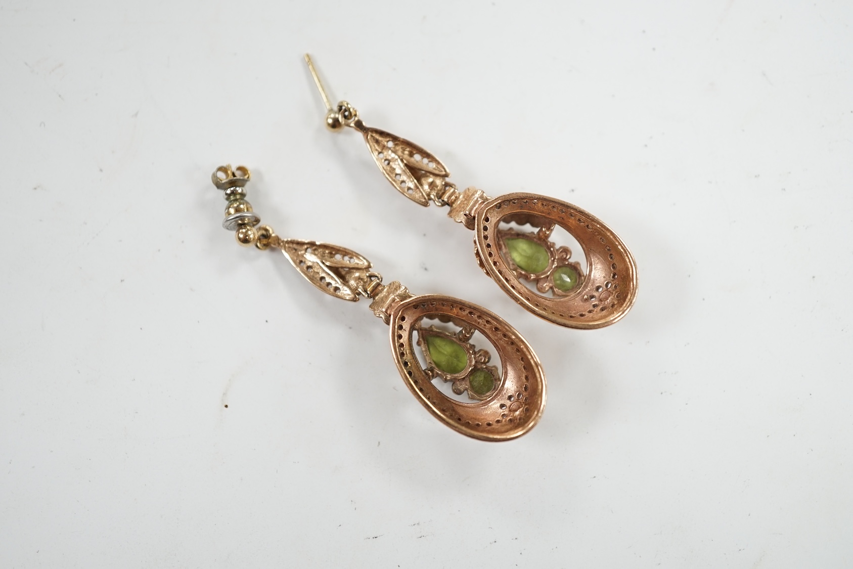 A pair of late 19th/early 20th century style yellow metal and two stone peridot set drop earrings, 48mm. Condition - poor to fair